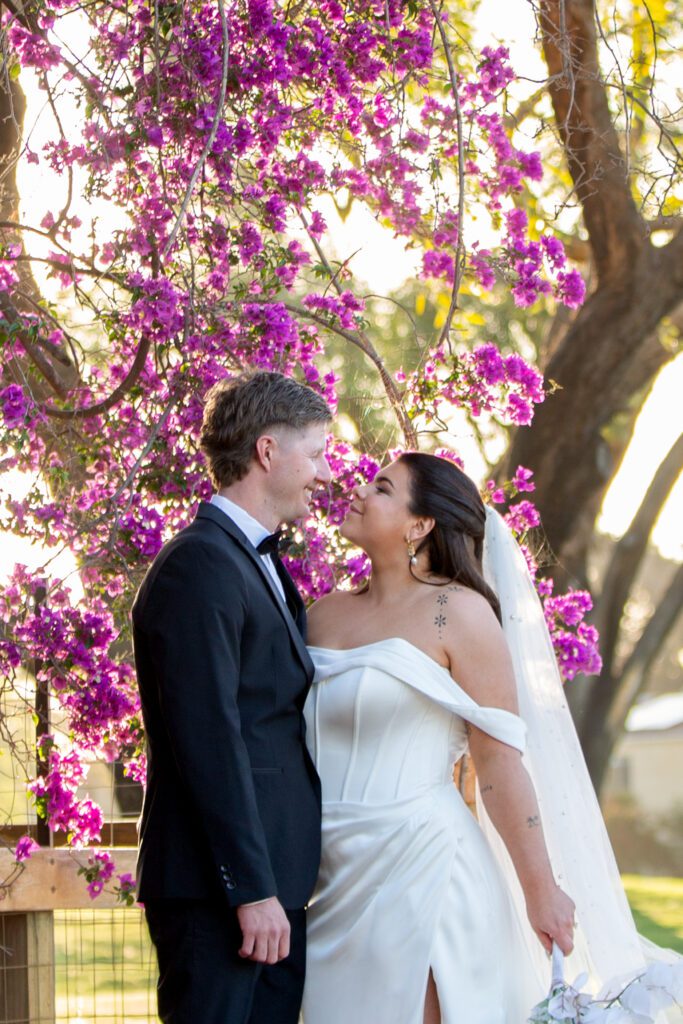Bride and groom under pink flowering trees at The Vines Resort wedding venue in Swan Valley, Perth.